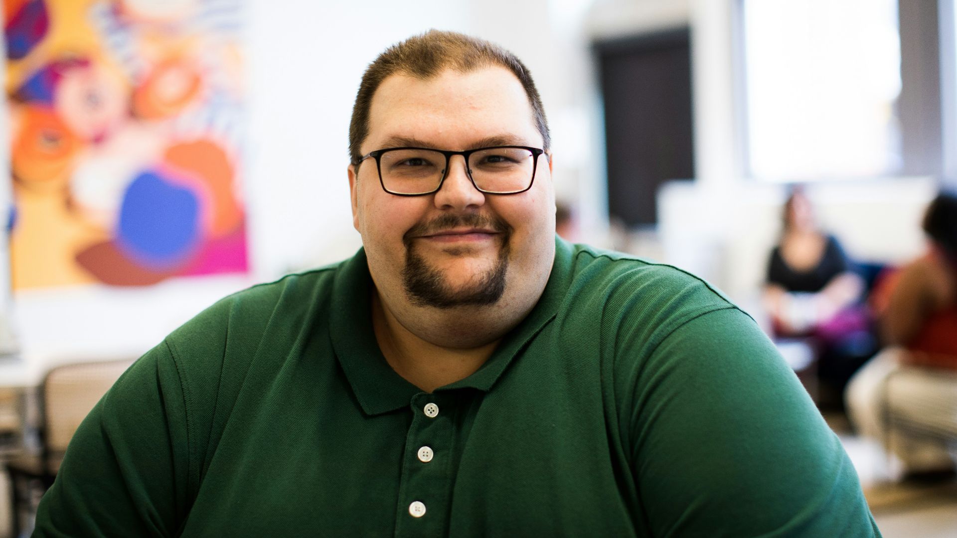 smiling man in green polo shirt wearing eyeglasses