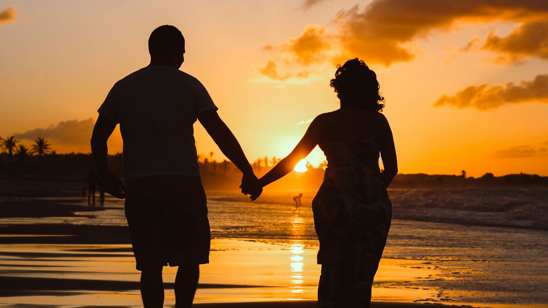 couple standing on body of water during golden hour
