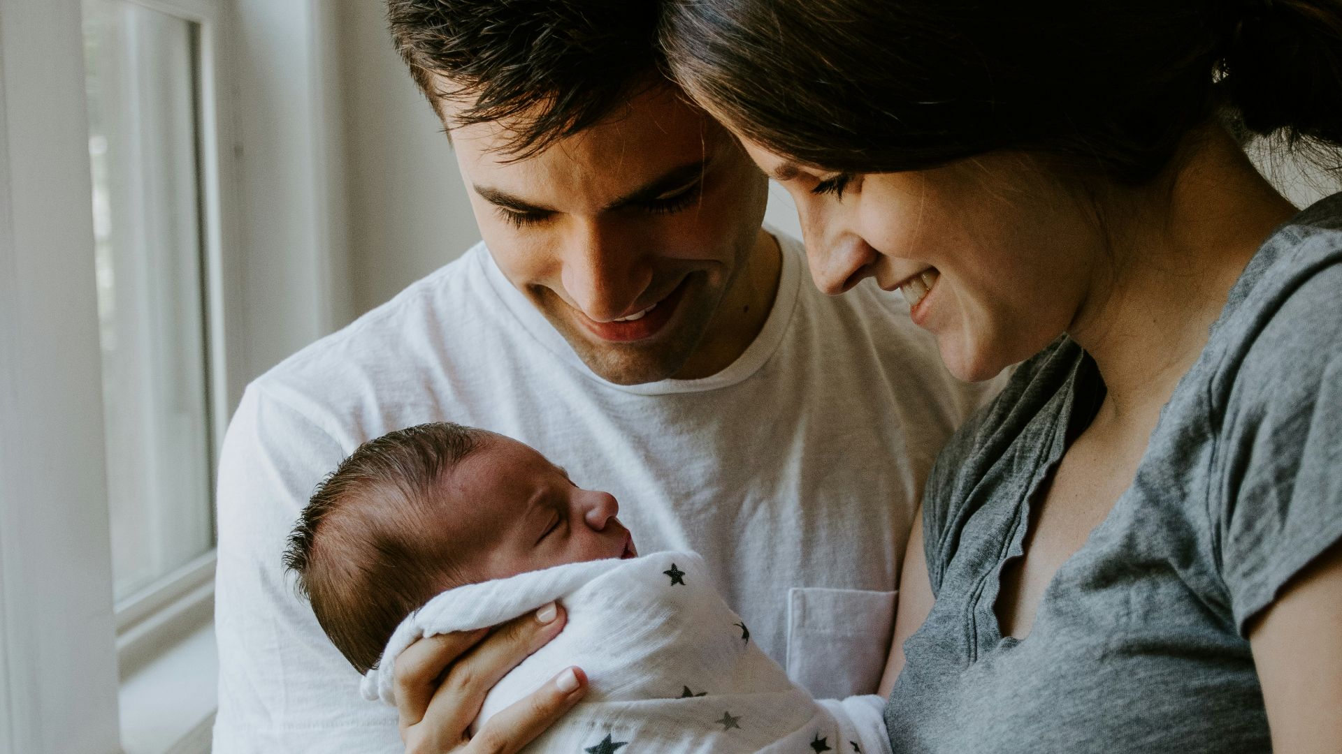 woman holding baby beside man smiling