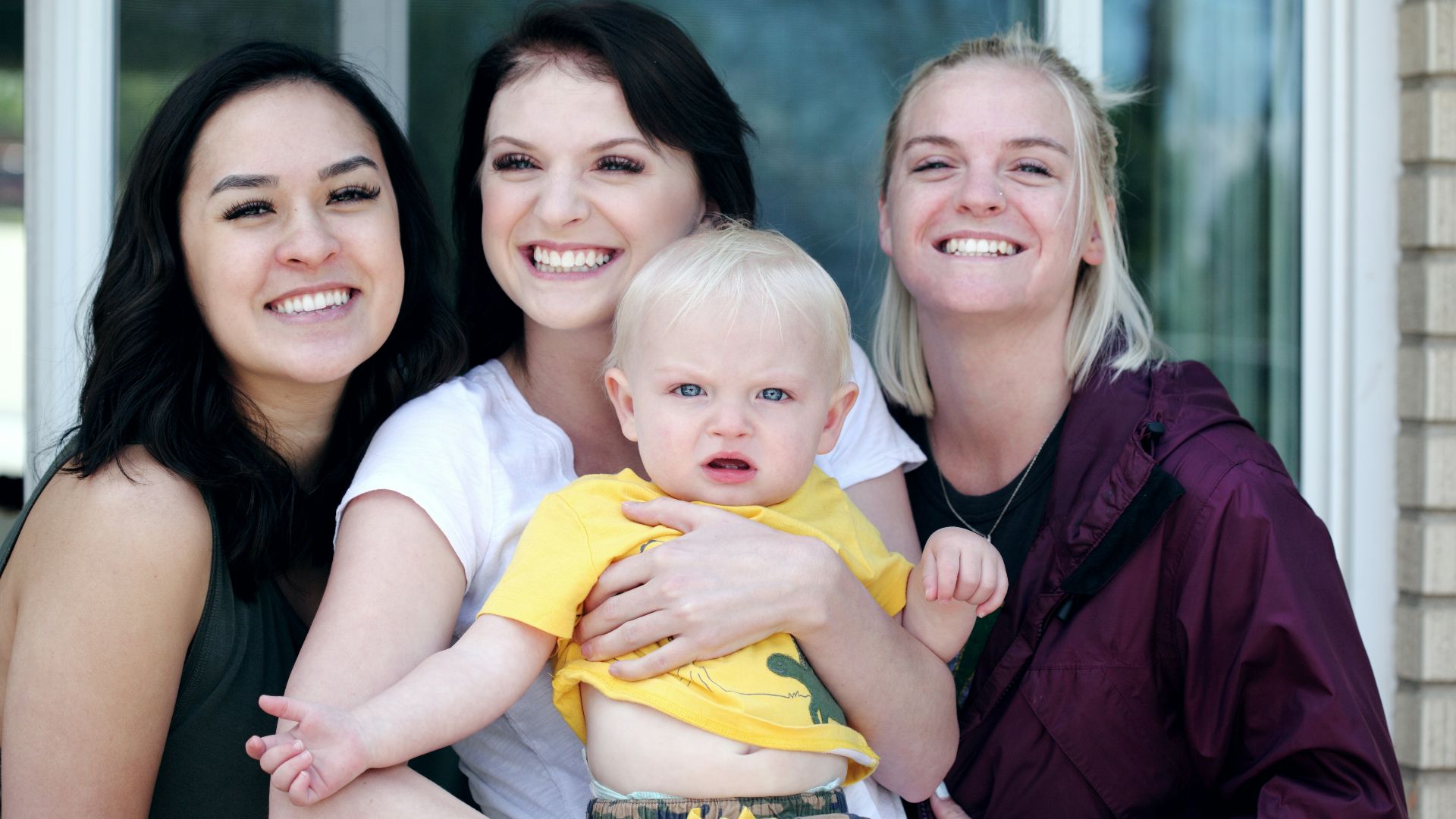 woman carrying baby with two ladies beside her smiling