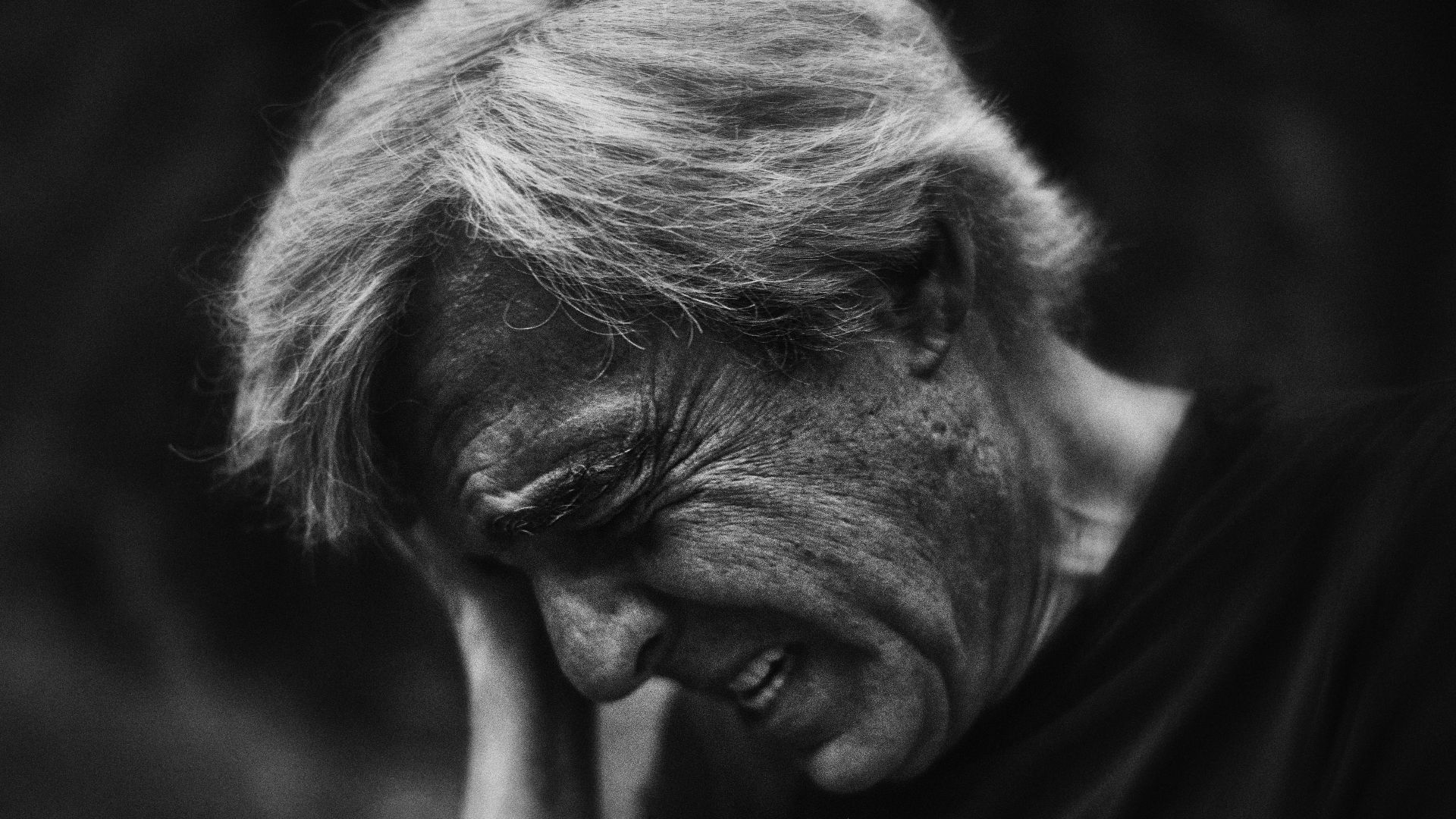 A black and white photo of a man with his hand on his face