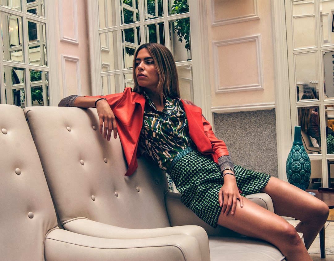 woman in red and black plaid dress shirt sitting on white leather armchair
