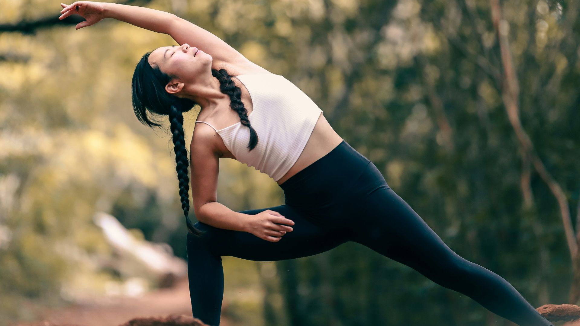 woman in white tank top and black leggings doing yoga during daytime