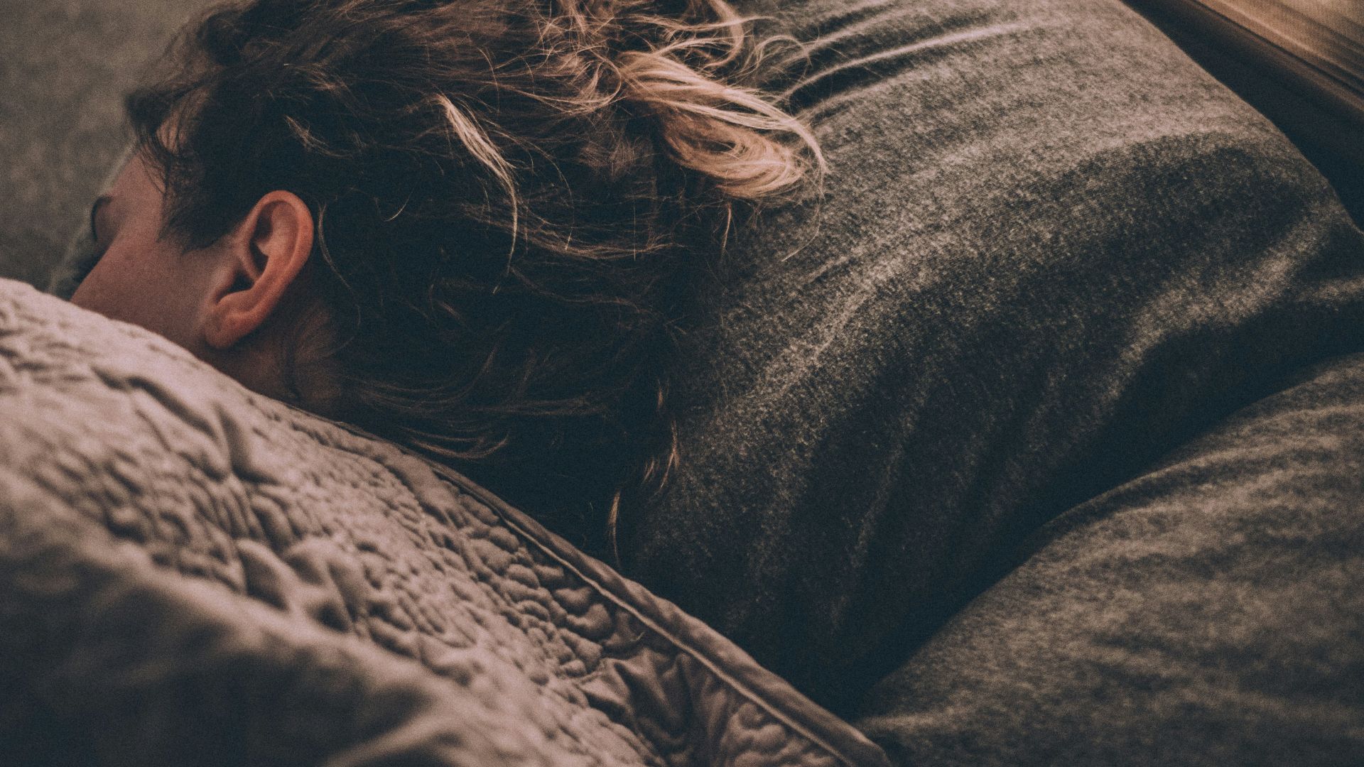 woman sleeping on bed under blankets