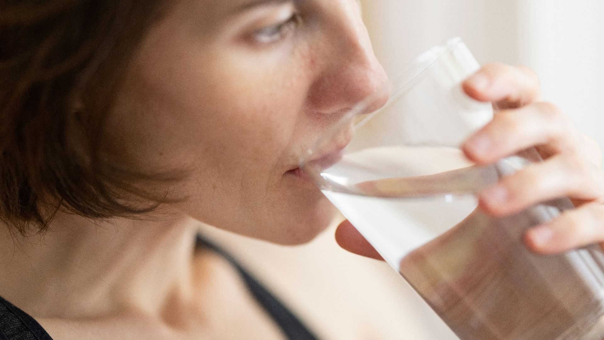 woman in black tank top drinking water