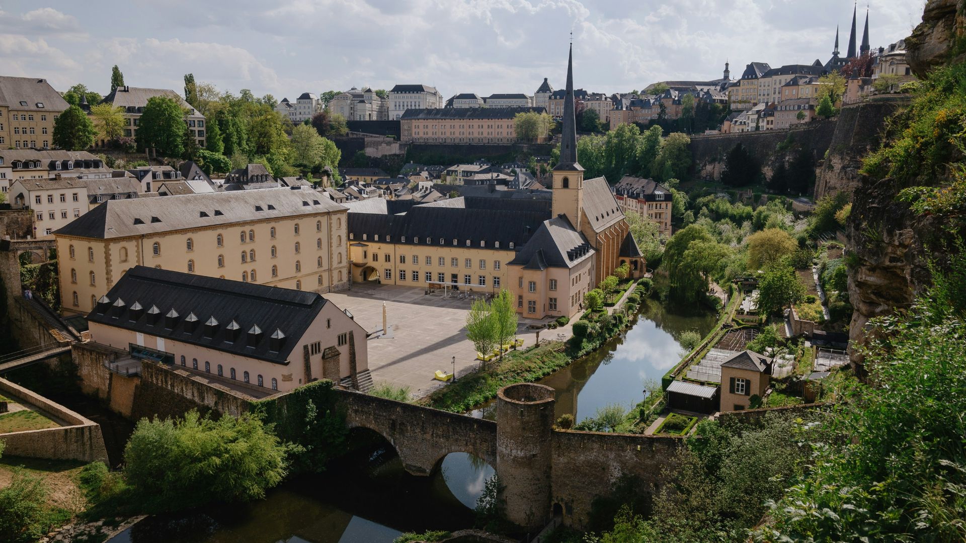 brown concrete building near green trees under white clouds during daytime