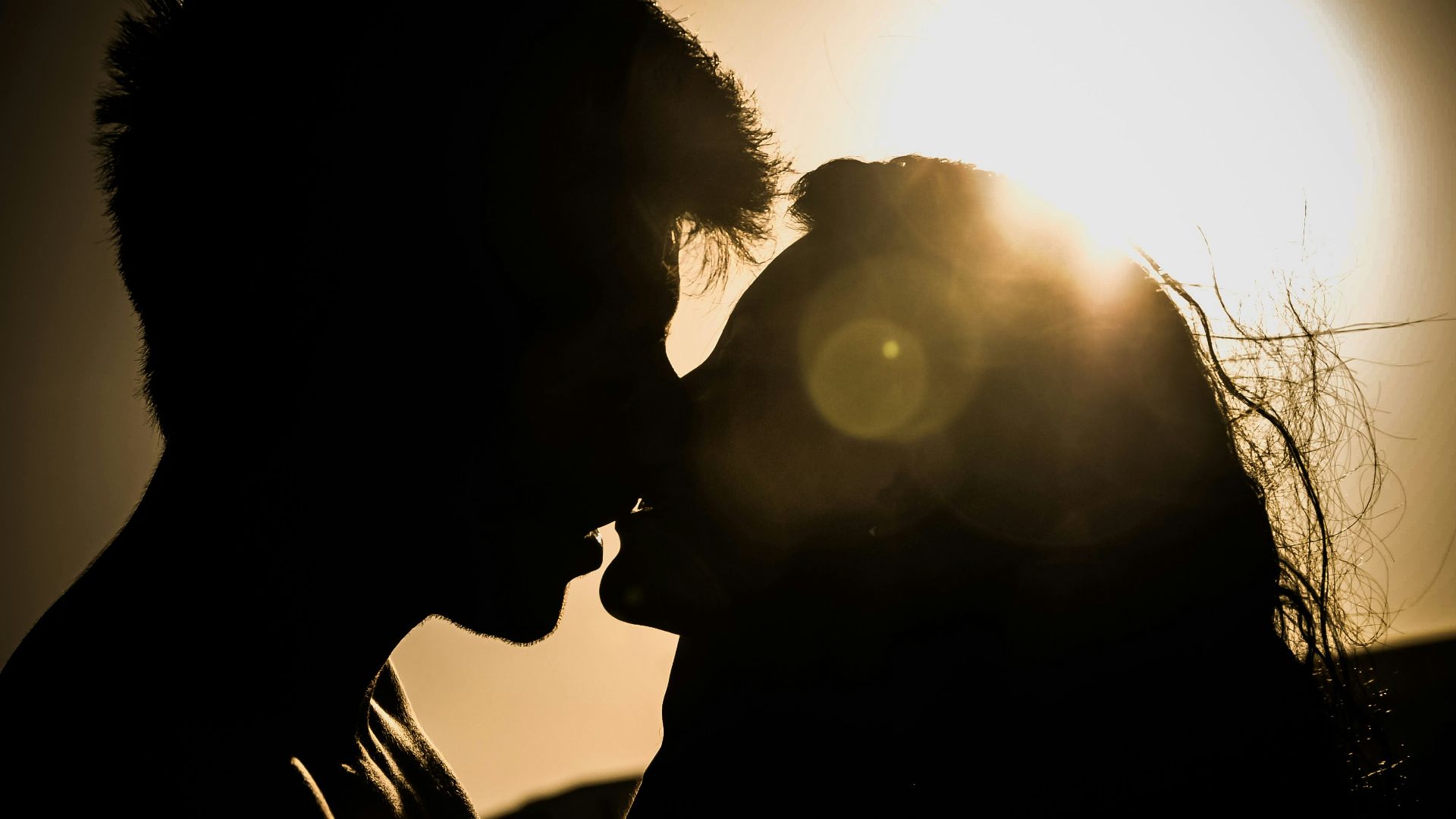 man and woman kissing under the sun
