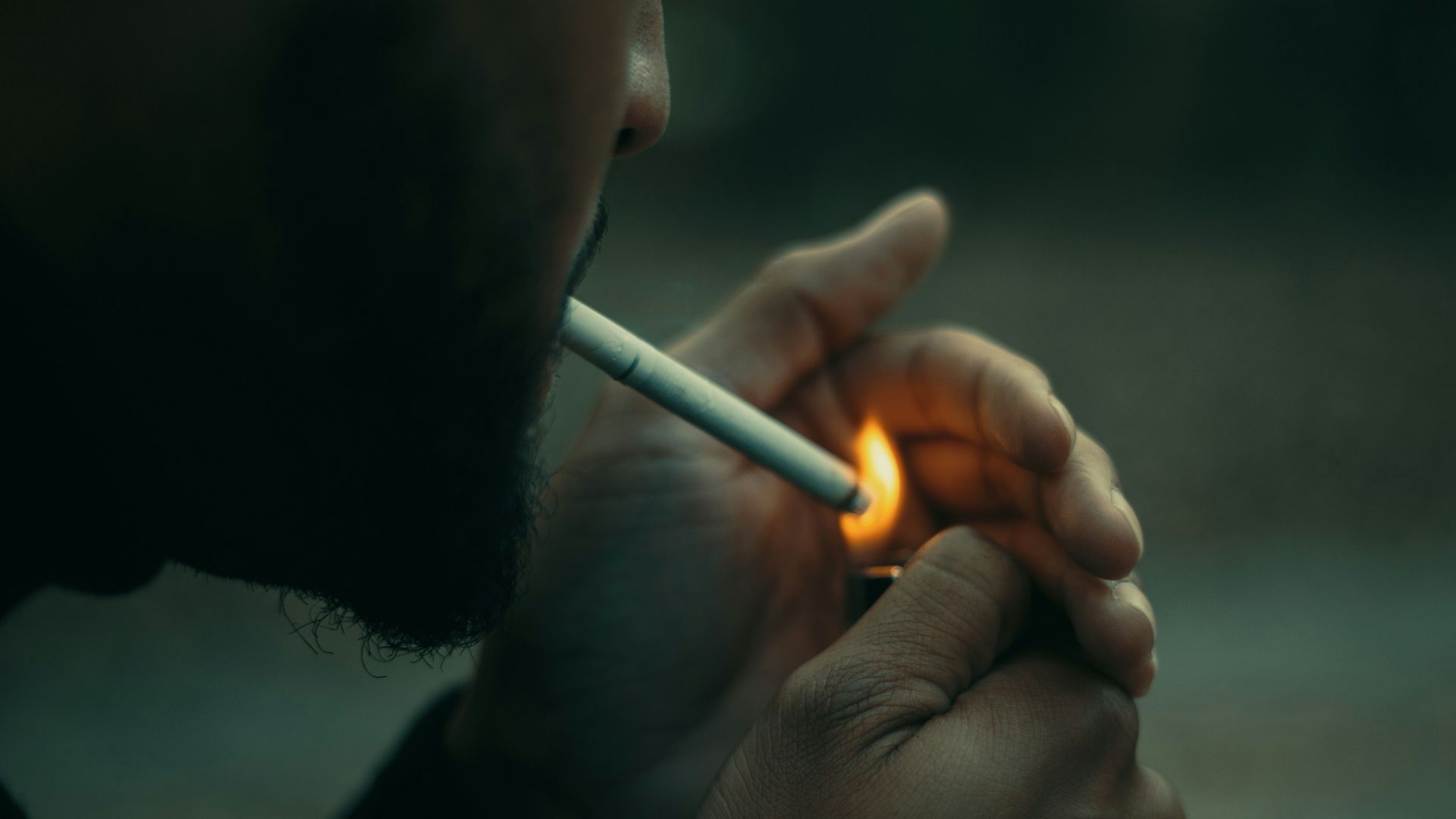 close-up photography of man using cigarette during daytime