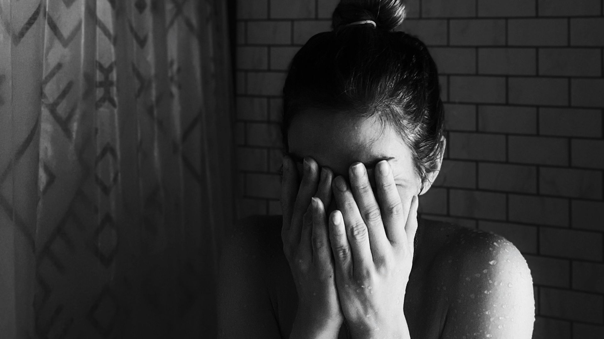 grayscale photo of woman covering her face with her hands