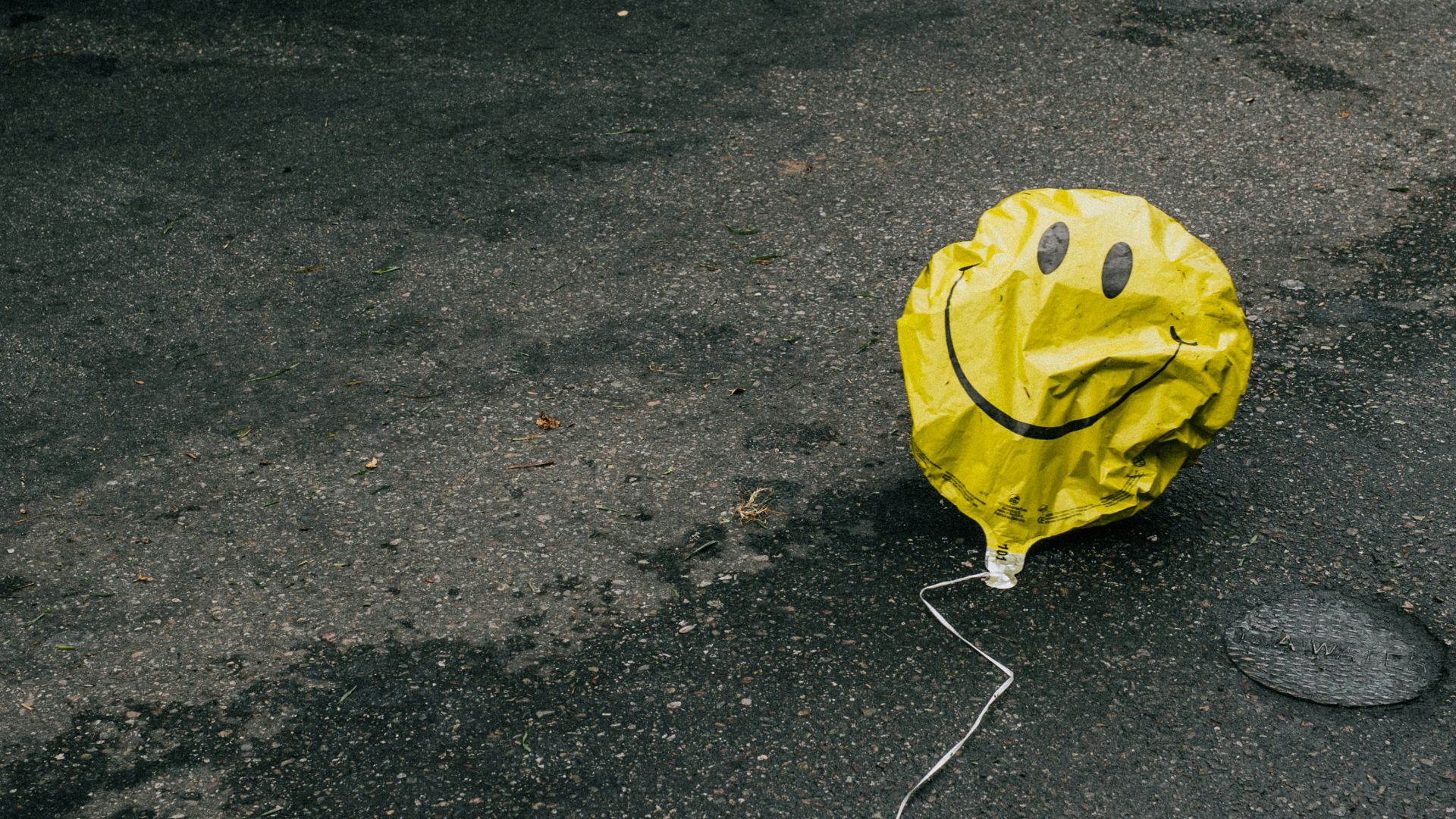 smiling emoji balloon beside black car during daytime