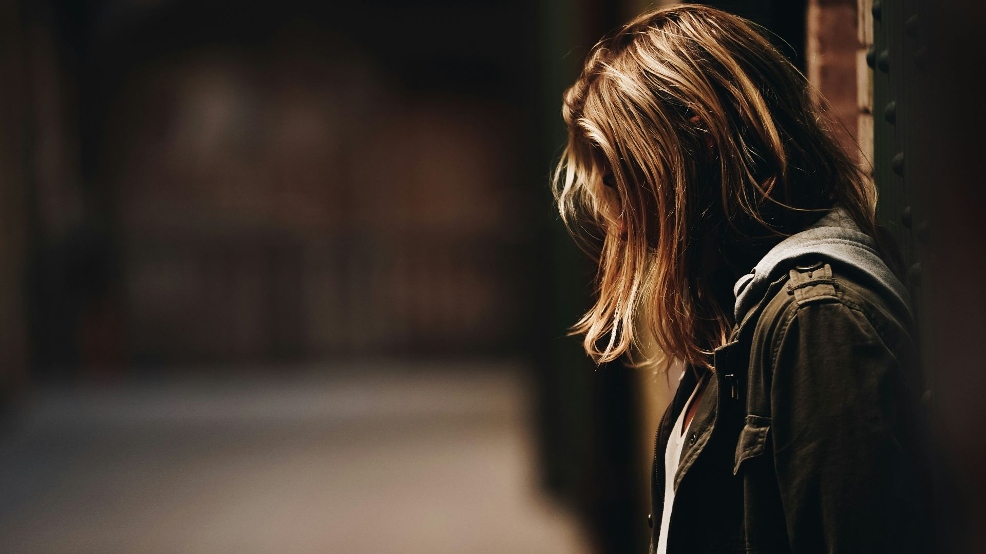 woman leaning against a wall in dim hallway