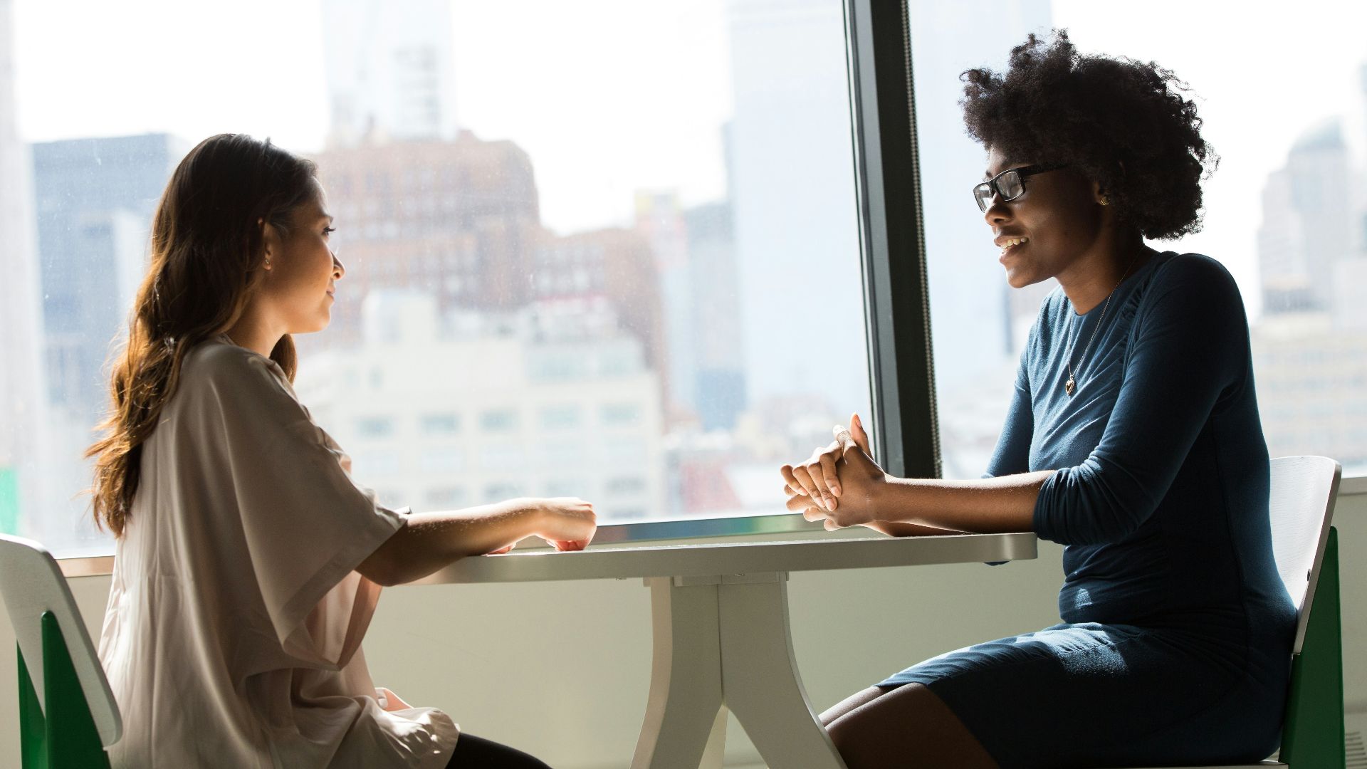 two women sitting beside table and talking
