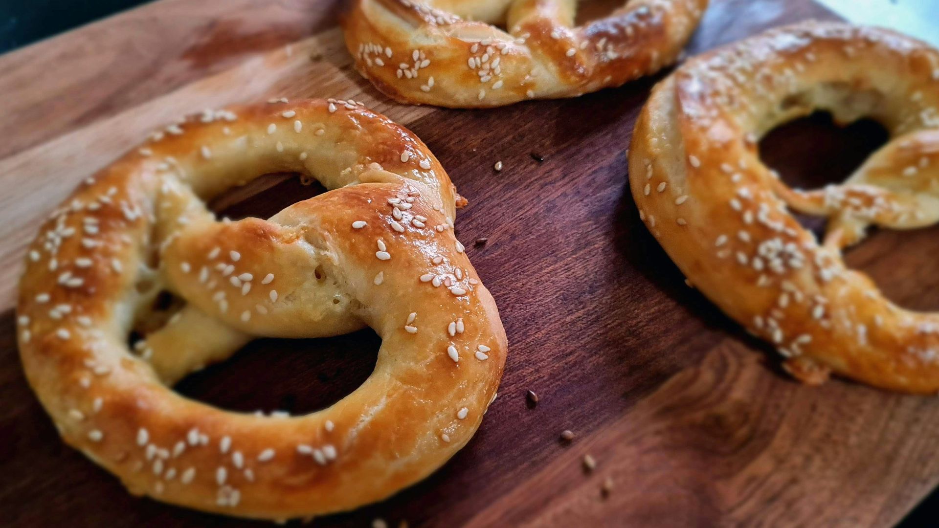 a wooden cutting board topped with three pretzels