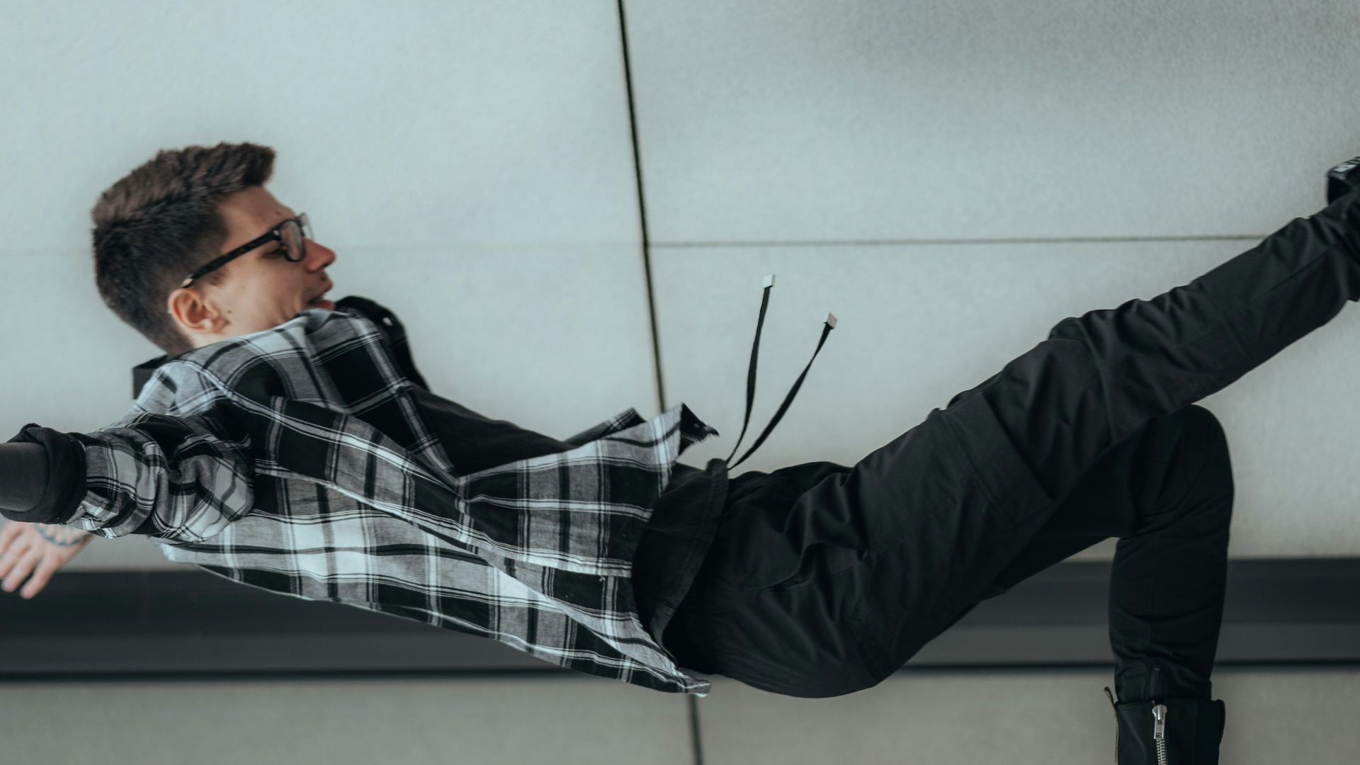 man in black and white plaid dress shirt and black pants lying on floor