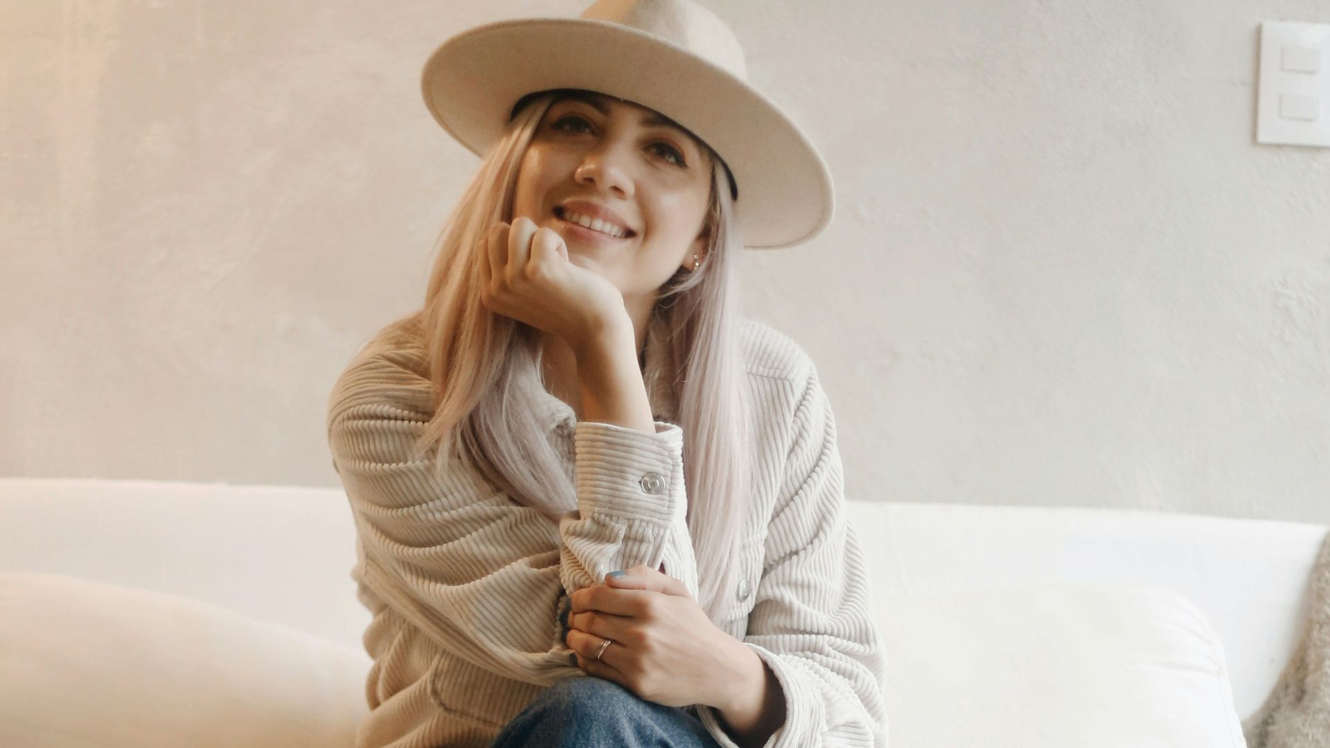 woman in white long sleeve shirt and blue denim jeans sitting on white couch