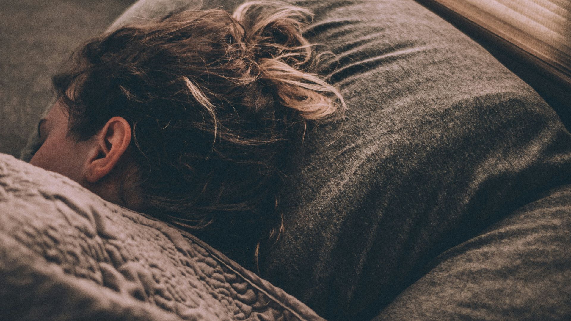 woman sleeping on bed under blankets