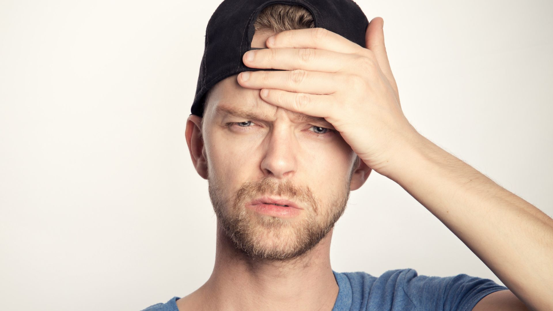 man in blue crew neck shirt covering his face