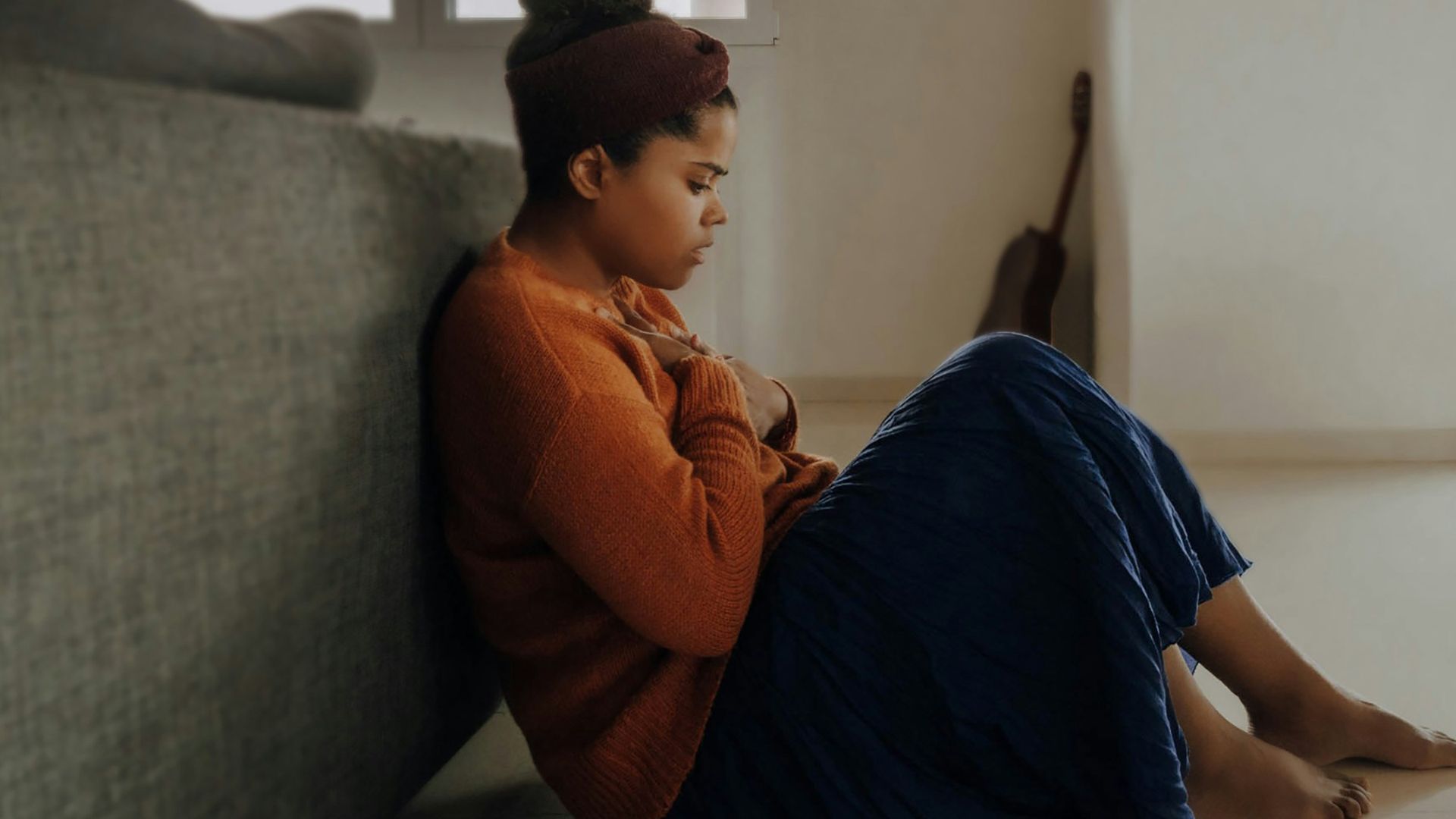 man in orange long sleeve shirt sitting on gray couch