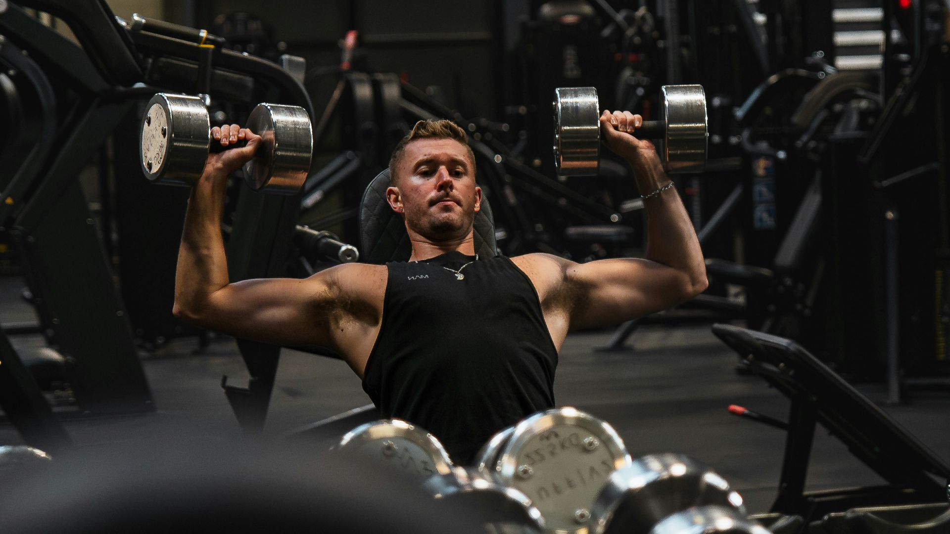 a man in a gym lifting a pair of dumbbells
