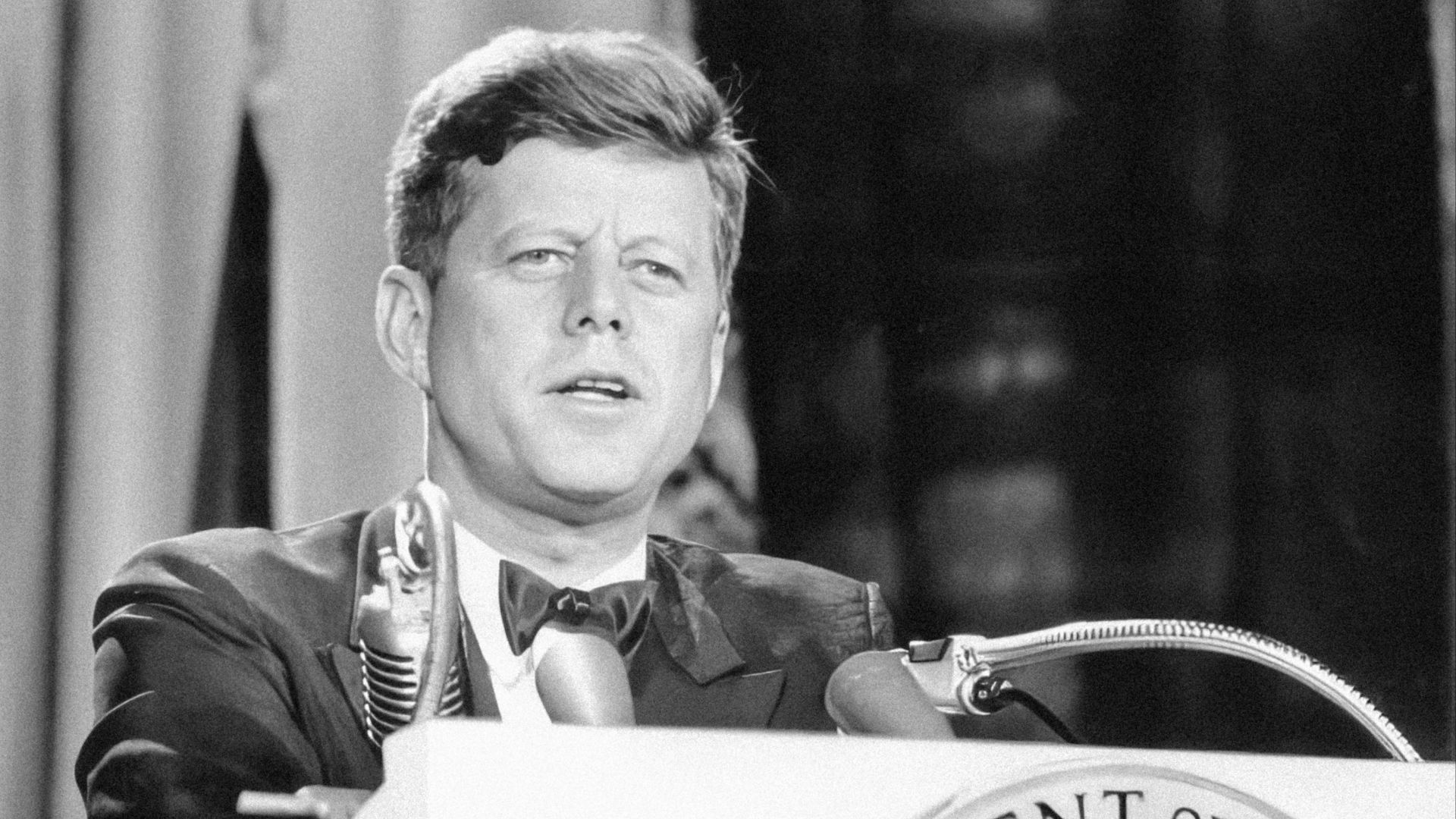 a man in a suit and tie standing at a podium