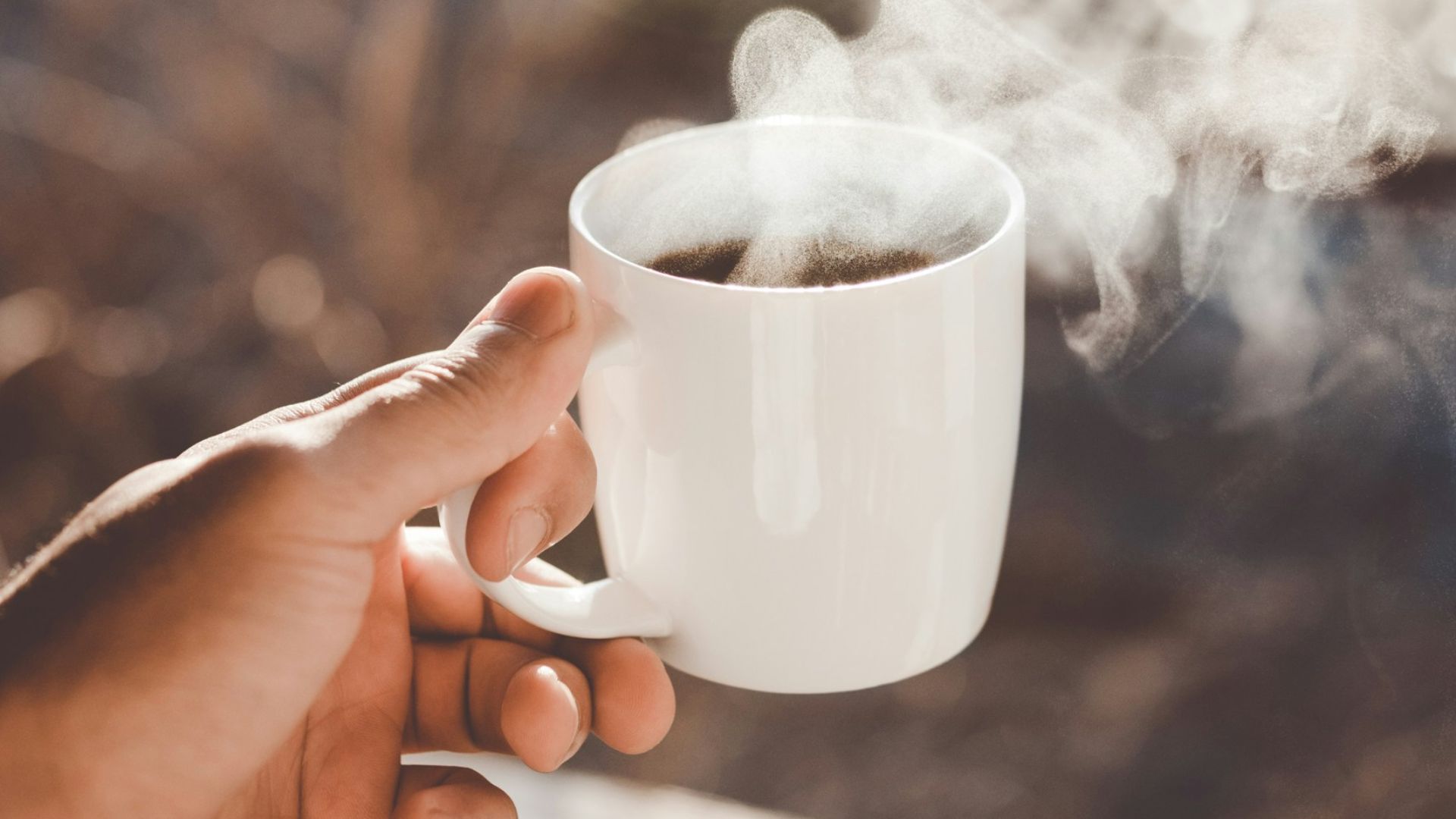person holding white ceramic cup with hot coffee