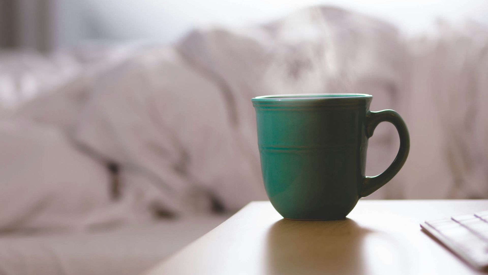 green ceramic mug on wooden desk