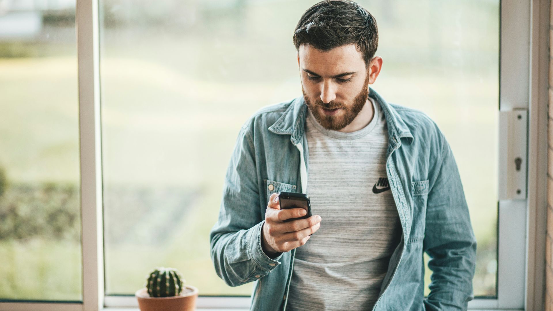 man holding a smartphone near the window
