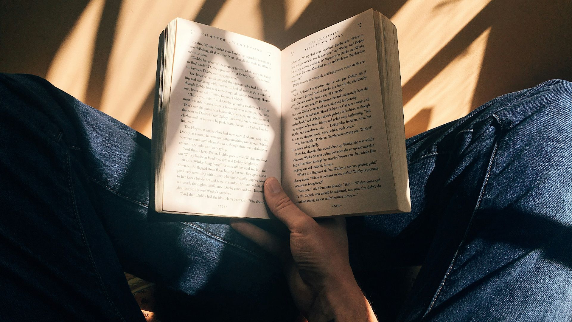 person holding book sitting on brown surface