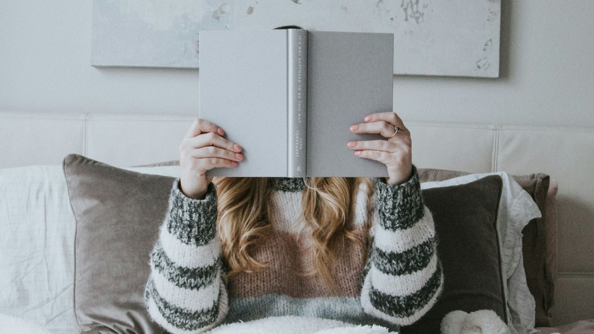woman sitting on bed while holding book