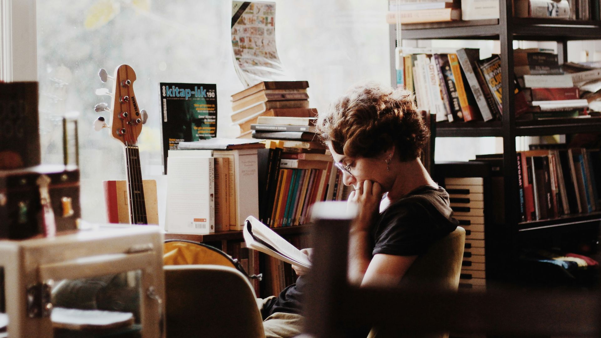 woman reading book sitting beside electronic keyboard