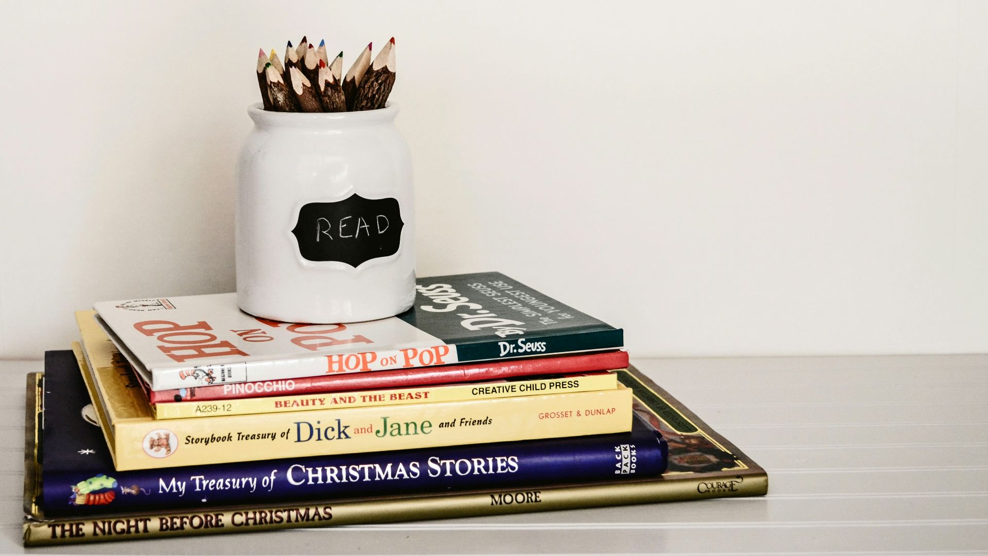white ceramic pencil organizer on top of stack of books