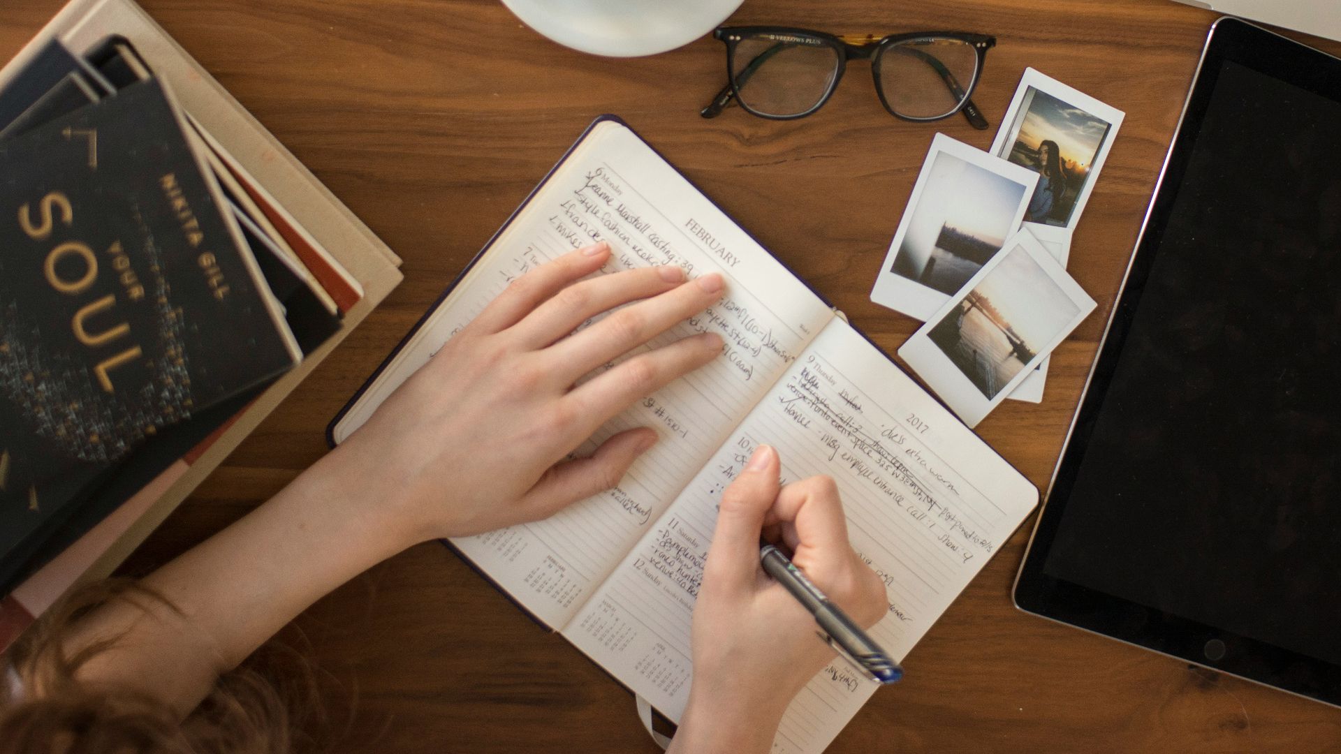 person holding ballpoint pen writing on notebook