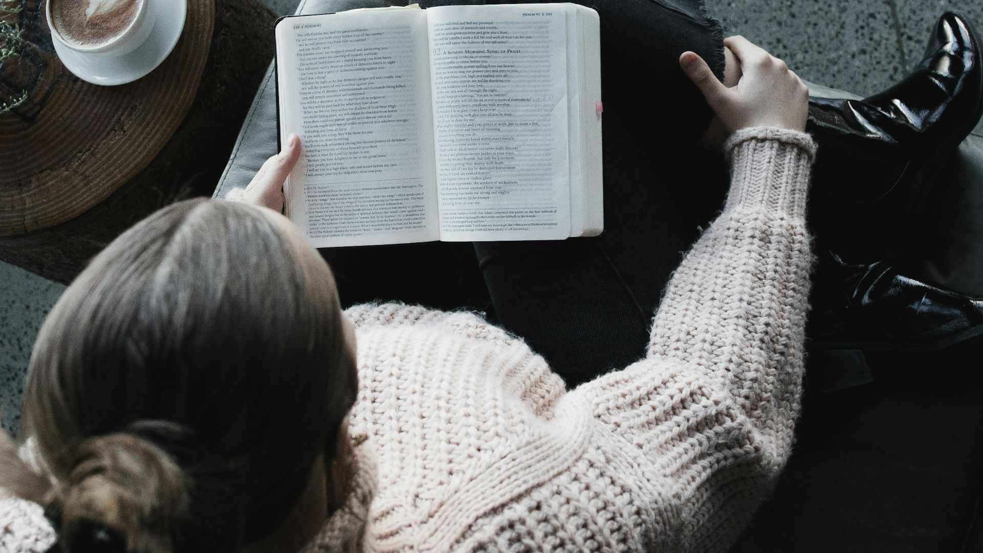 woman in white sweater reading book