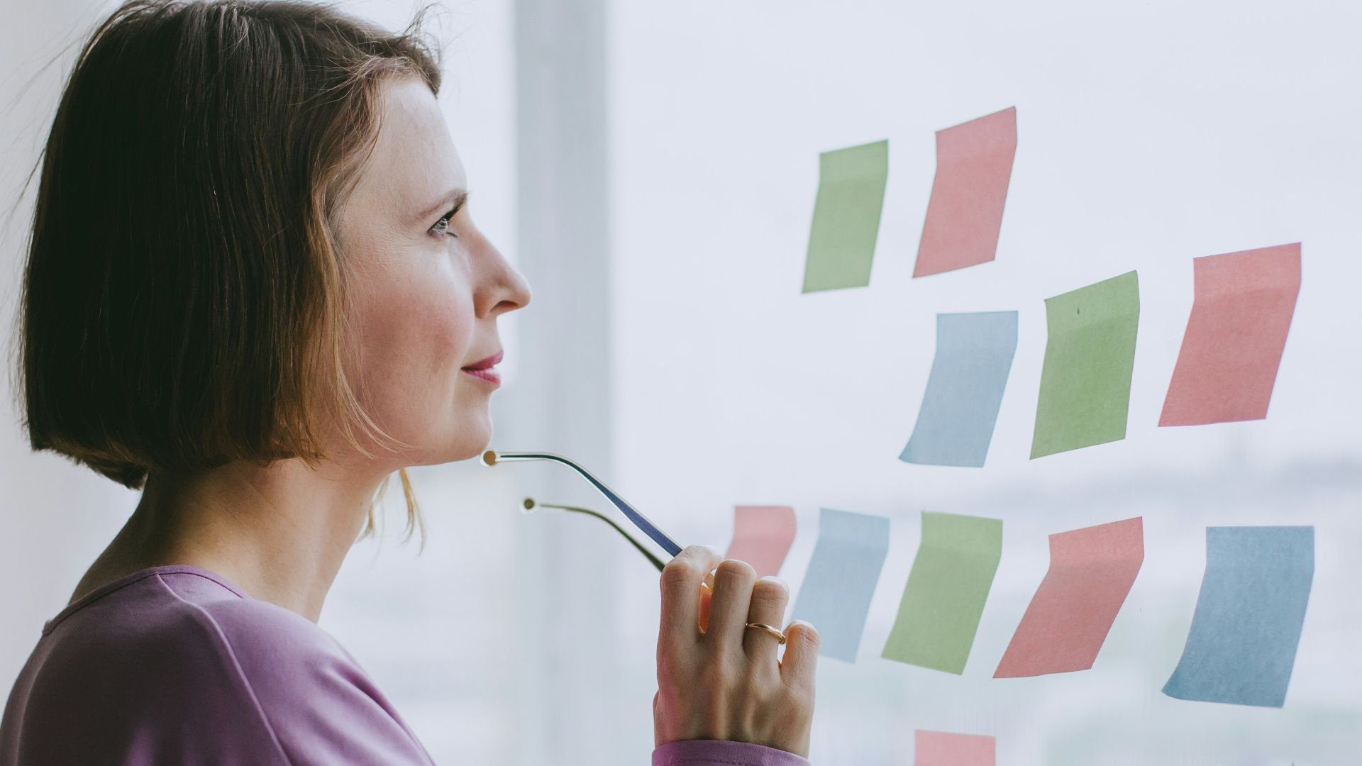 a woman looking out a window with sticky notes on it