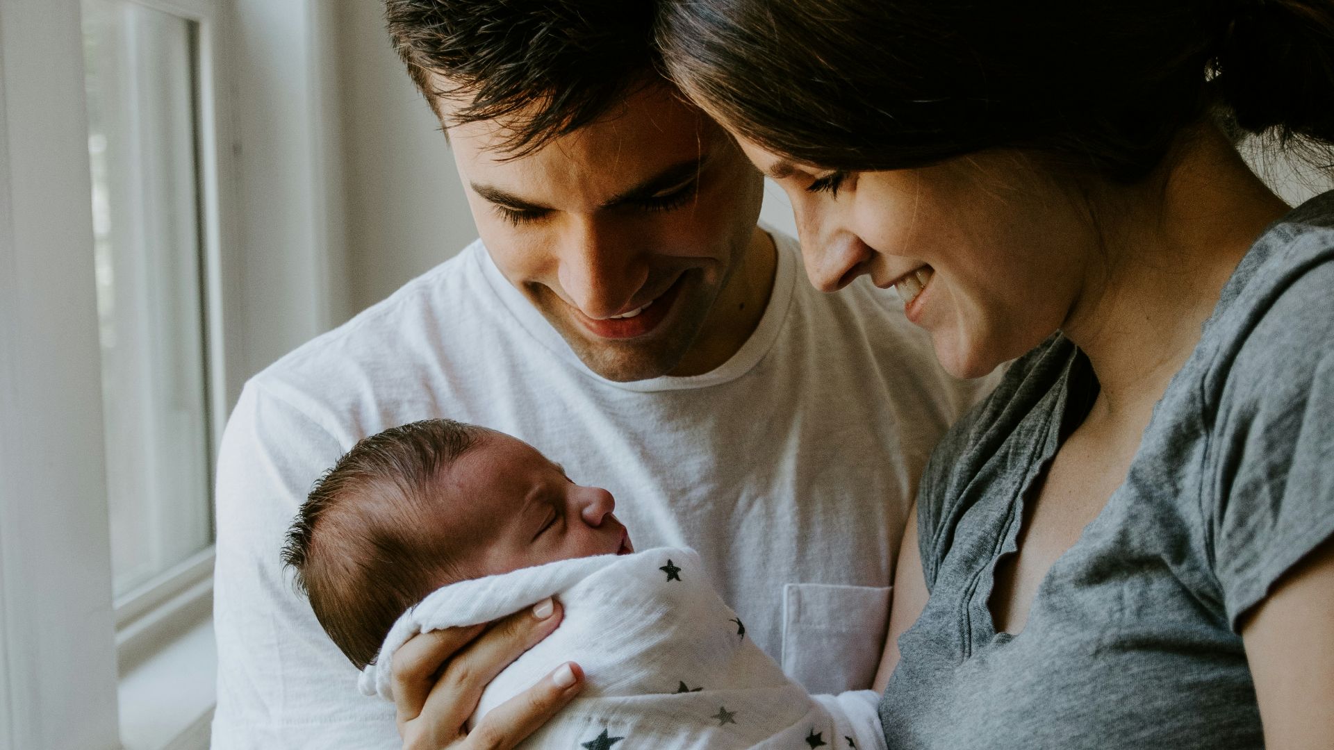 woman holding baby beside man smiling