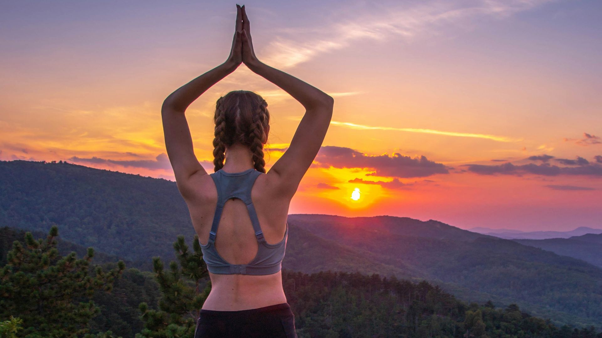 woman in black leggings standing on rock formation during sunset