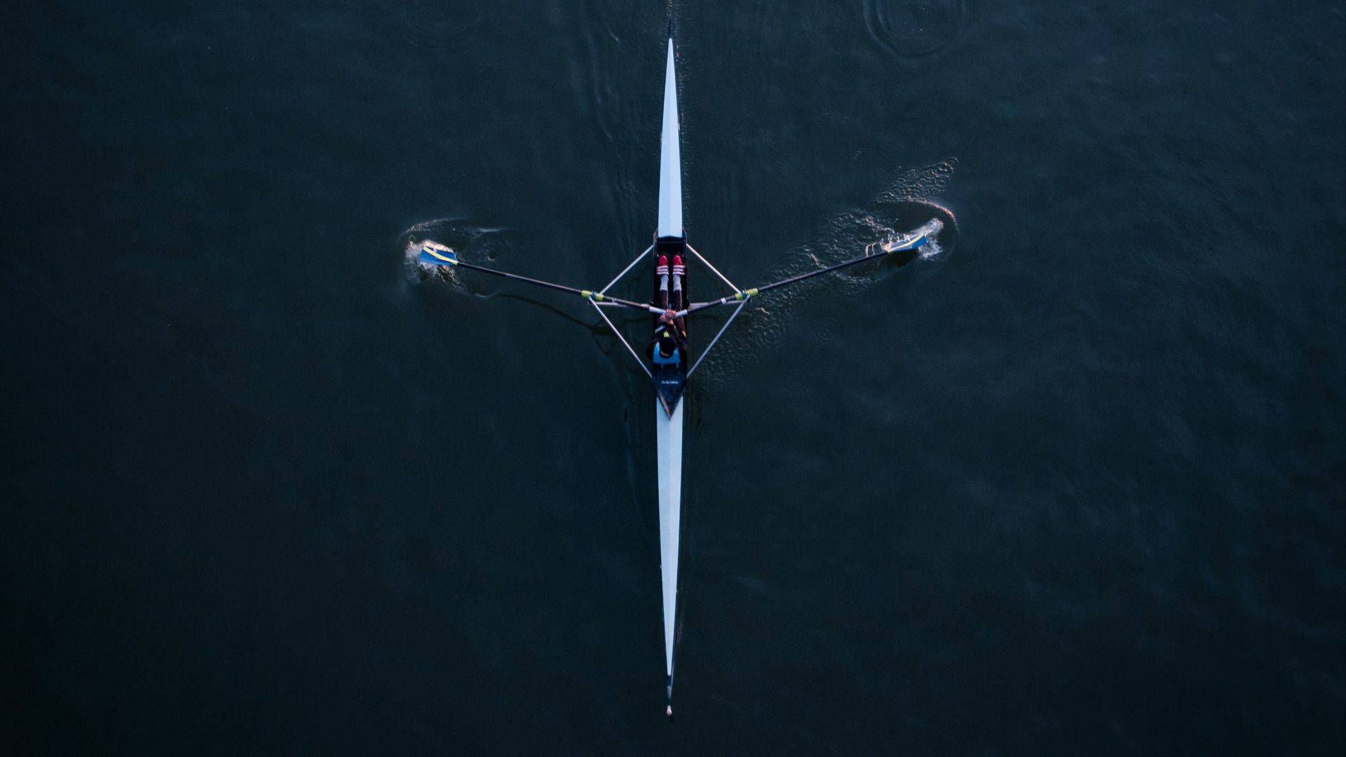 two people rowing a boat on a large body of water