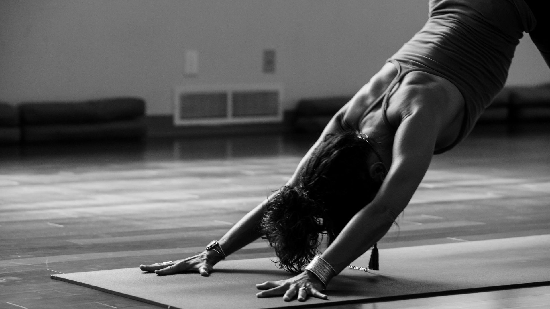 woman in black tank top and black pants bending her body on floor