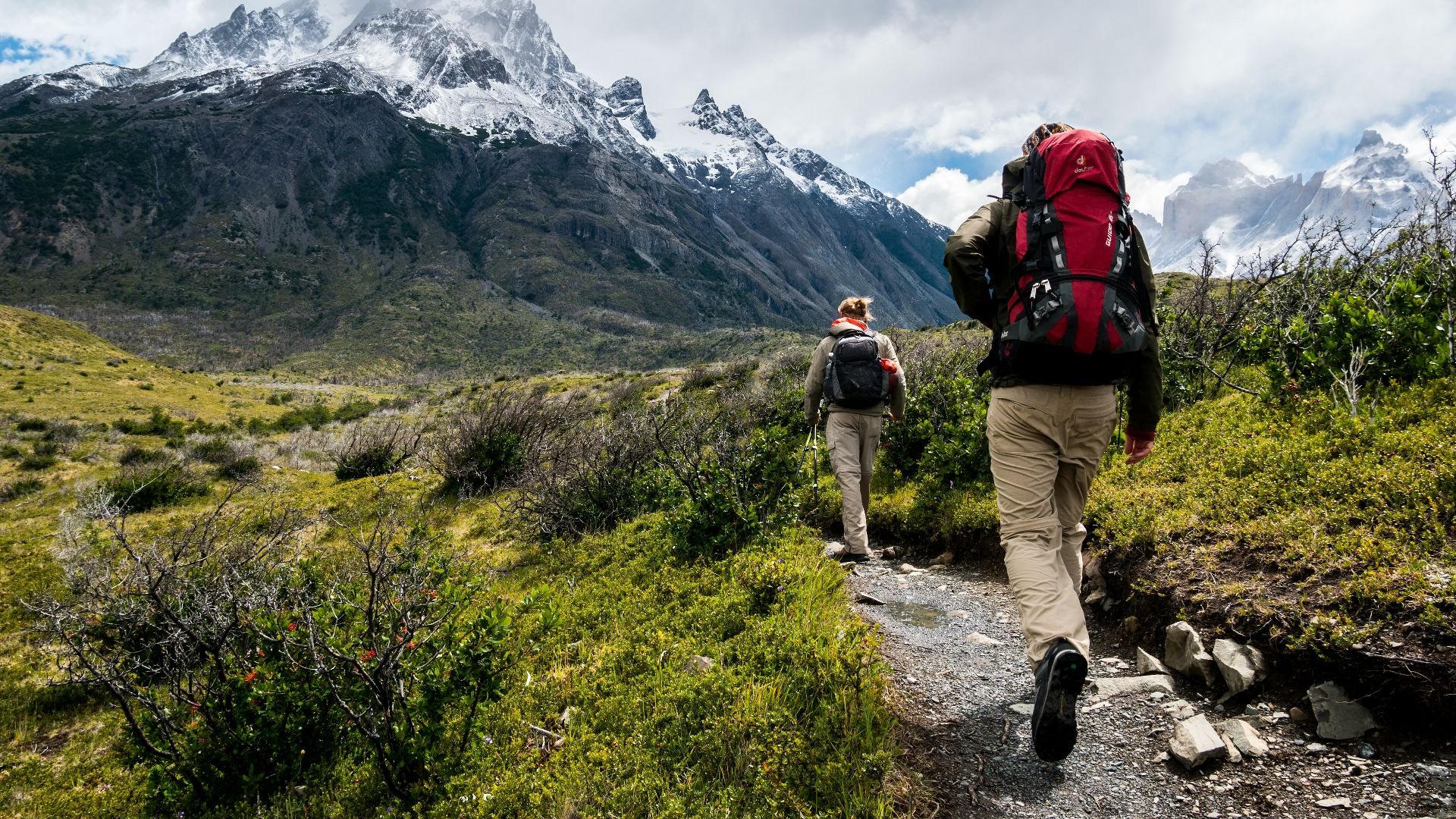 two person walking towards mountain covered with snow