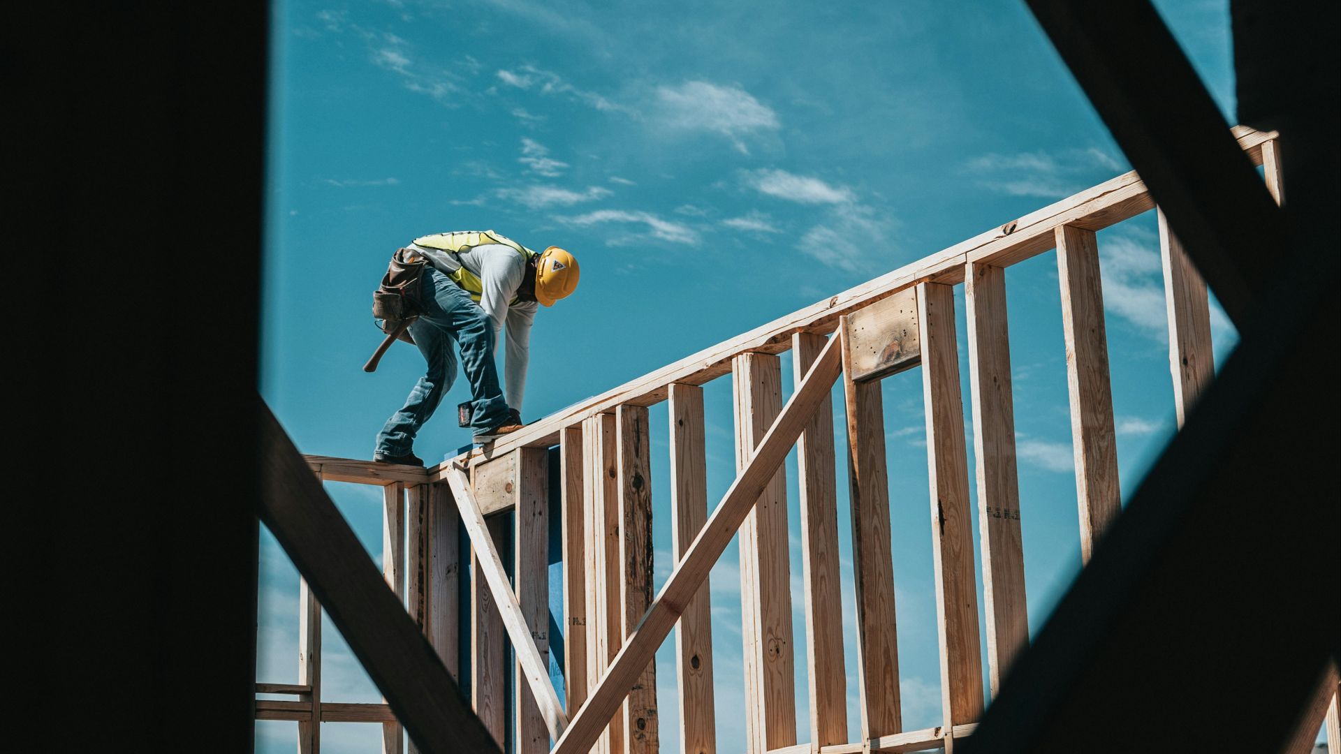 man in yellow shirt and blue denim jeans jumping on brown wooden railings under blue and