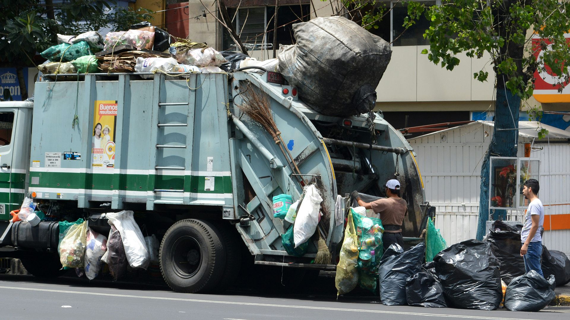 man in green jacket standing beside green truck during daytime