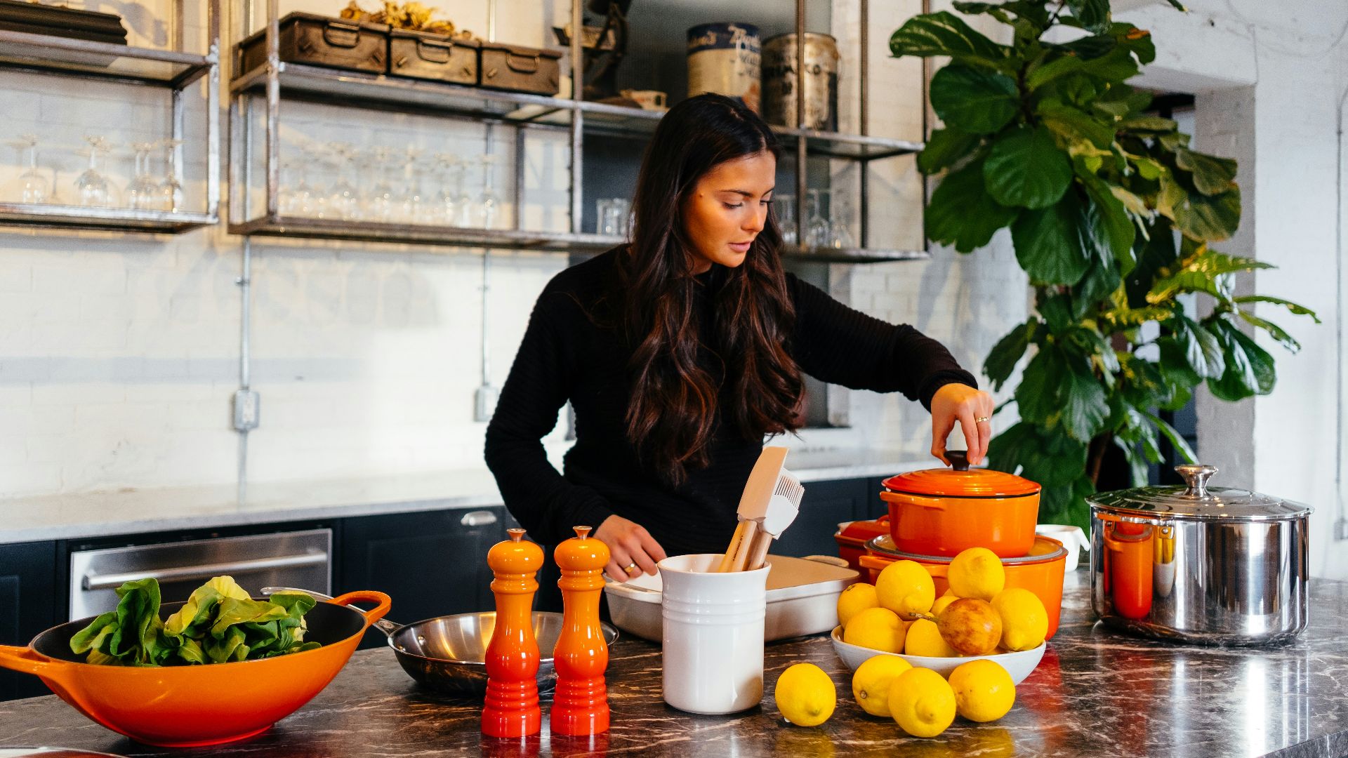 woman standing in front of fruits holding pot's lid