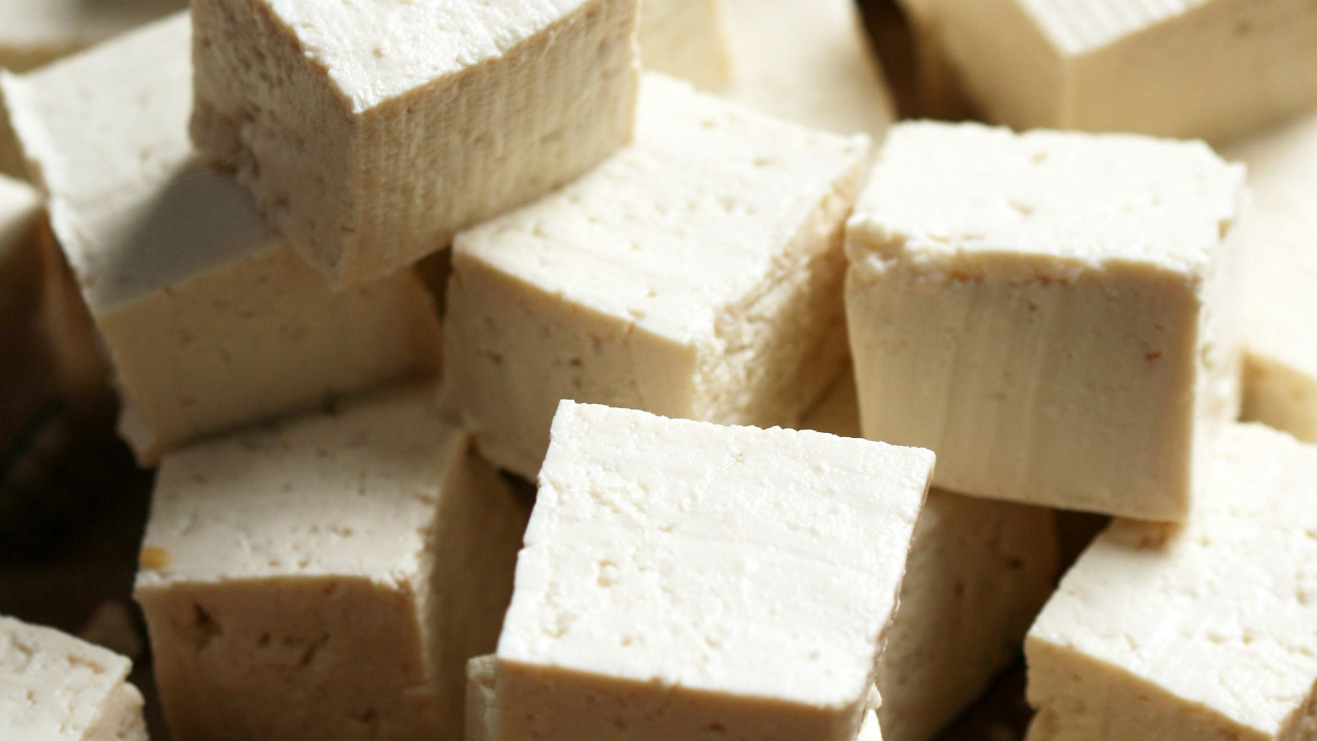 A pile of tofu cubes sitting on top of a cutting board
