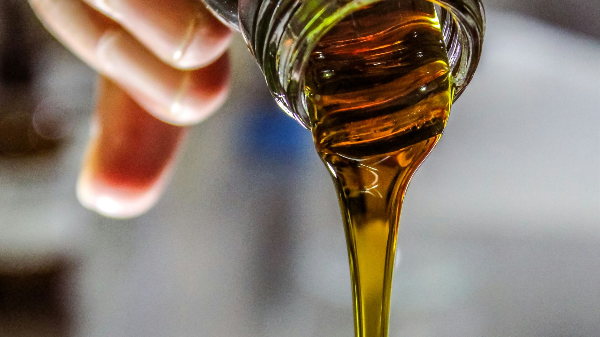 person holding clear drinking glass with brown liquid