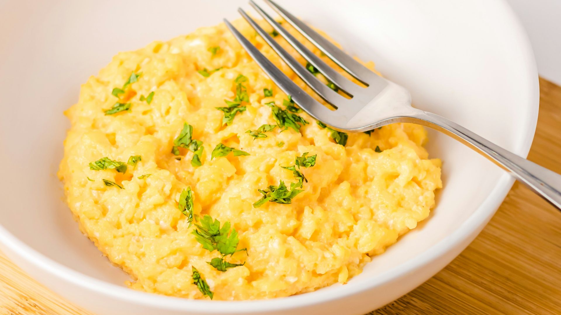 a bowl of scrambled eggs next to a slice of bread