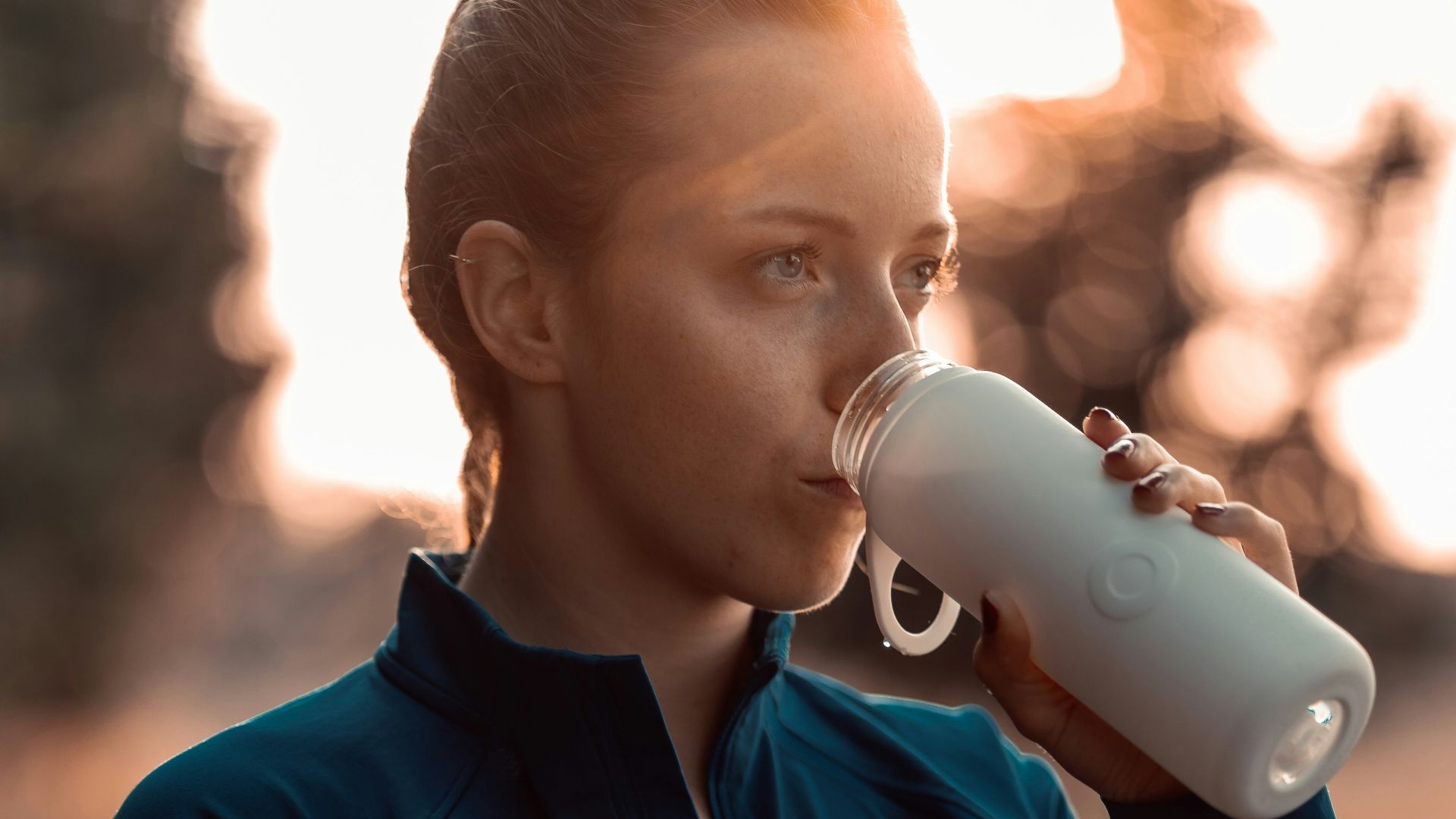 a woman drinking from a white cup