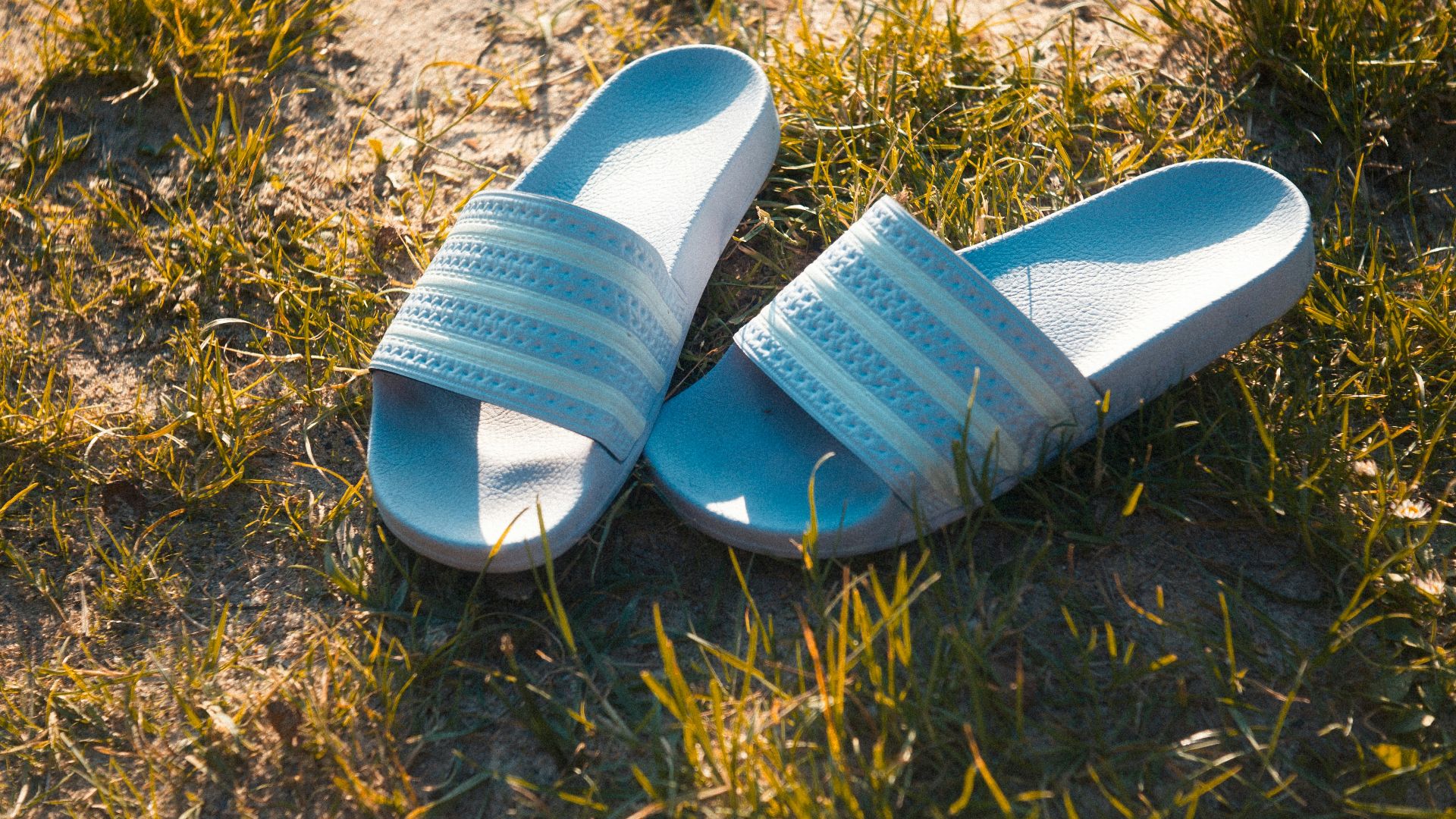 blue and white slide sandals on brown grass