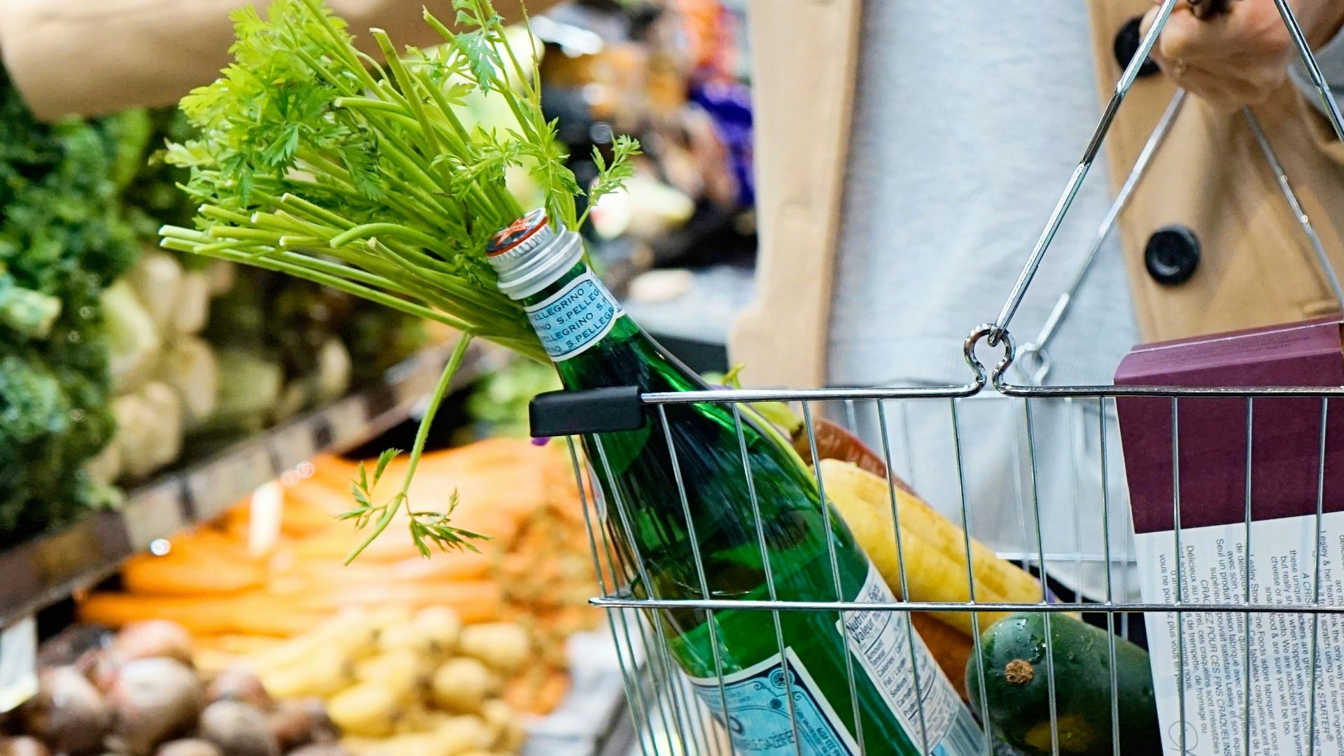 woman in white coat holding green shopping cart