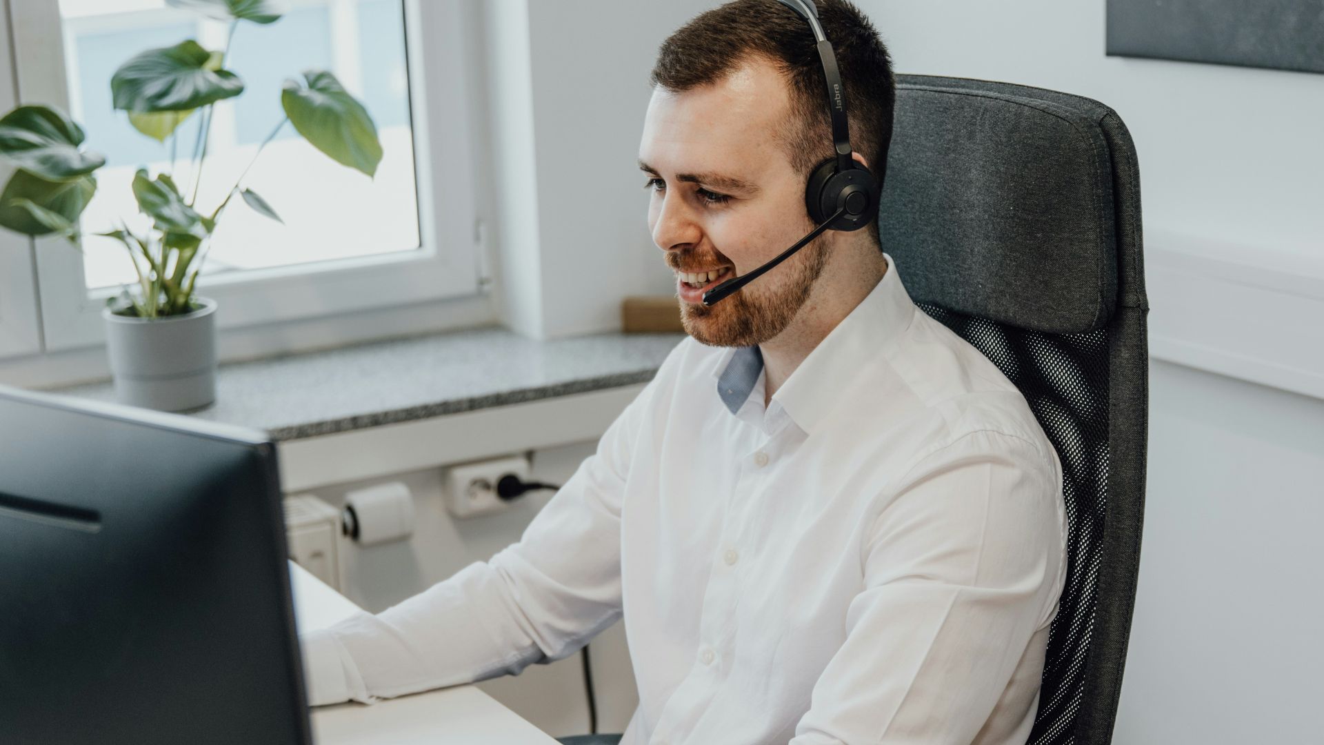 a man wearing a headset sitting in front of a computer