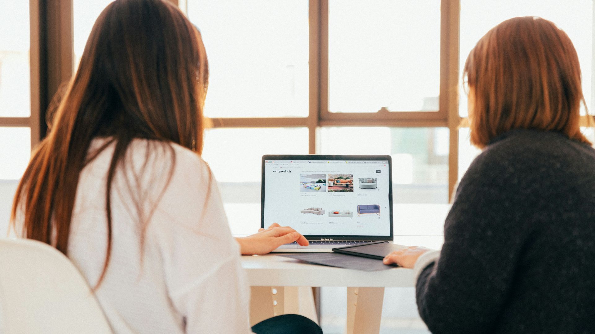 two women talking while looking at laptop computer